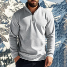 Man wearing a light grey quarter zip jumper with dark jeans in the mountains | Chaps London