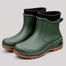 Green ankle rain boots with black ribbed knit cuffs and brown lugged soles, three quarter view.
