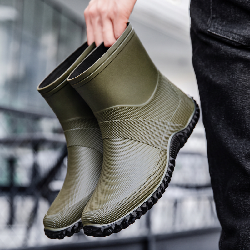 Green rubber ankle boots for men, held in the hand