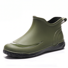 Green short welly with a black treaded sole and pull tab, side view