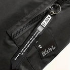 Black bomber jacket zipper closeup with pull tab and fabric label | Chaps London