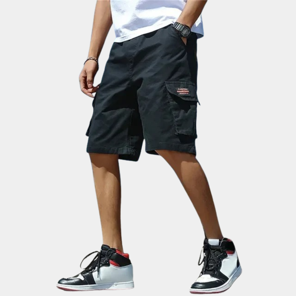 Black cargo shorts with side pockets worn by man, paired with sneakers | Chaps London