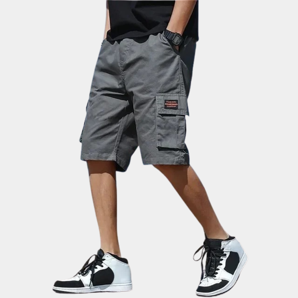 Gray cargo shorts with side pocket flaps worn by man standing | Chaps London