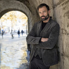 Man with arms crossed in a charcoal corduroy jacket and waistcoat, leaning in a stone archway | Chaps London