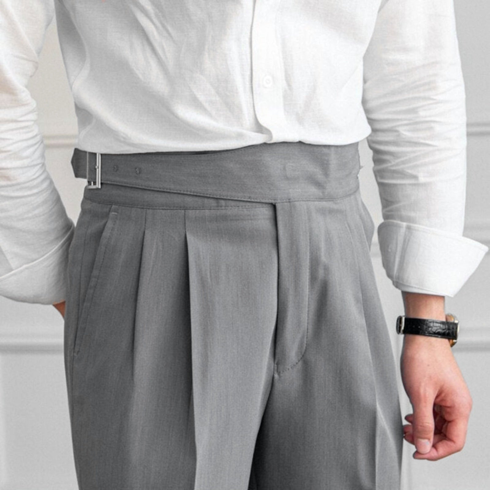 Man wearing gray pleated high-waisted trousers with adjustable side buckle closure | Chaps London