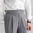Man wearing gray pleated high-waisted trousers with adjustable side buckle closure | Chaps London
