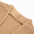 Close-up of tan knitted cardigan collar and shoulder seam, flat lay | Chaps London