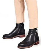 Black leather ankle boots with side zipper, worn by person, brown sole | Chaps London