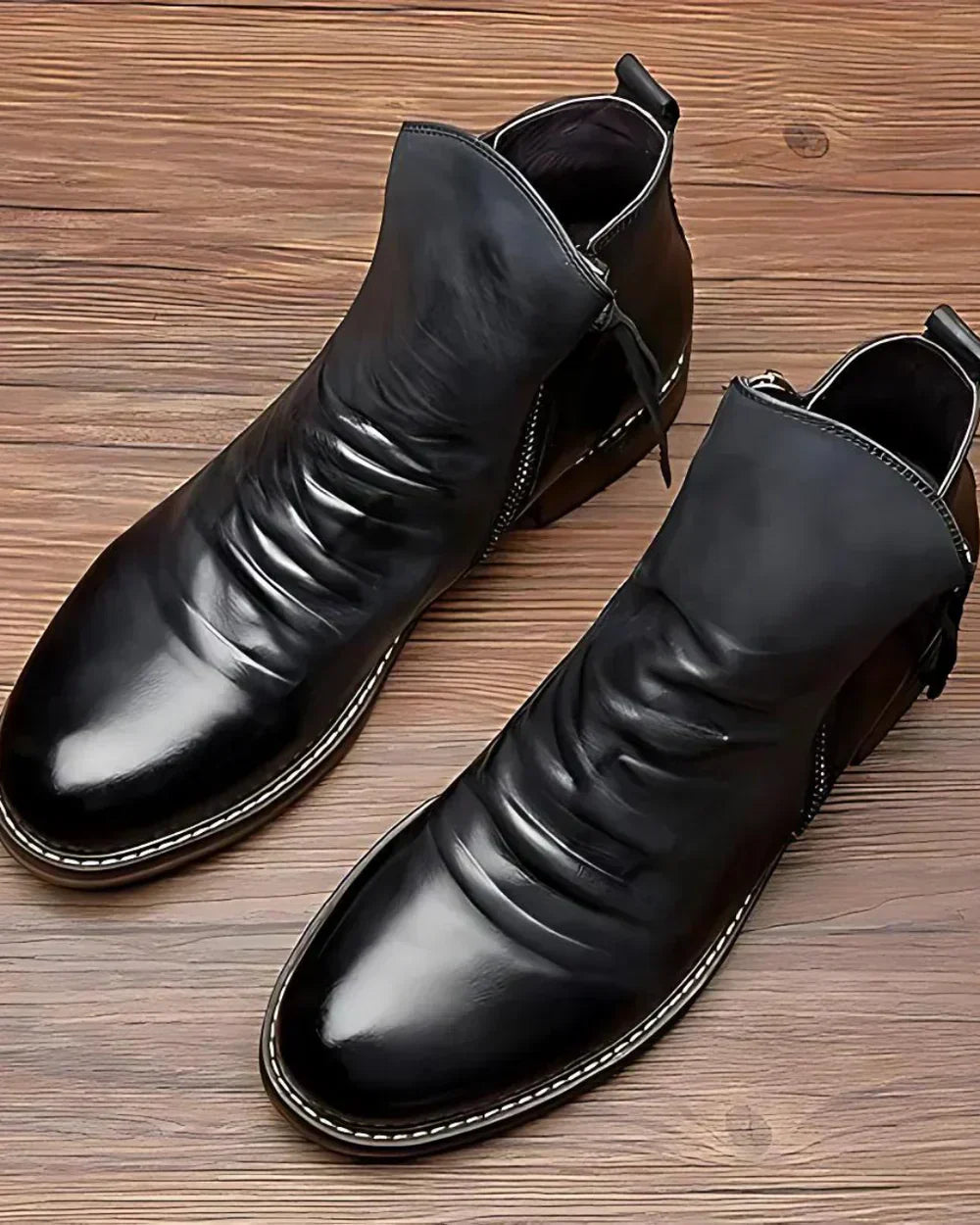 Black leather ankle boots with ruched wrinkled texture, displayed flat on wood | Chaps London