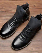 Black leather ankle boots with ruched wrinkled texture, displayed flat on wood | Chaps London