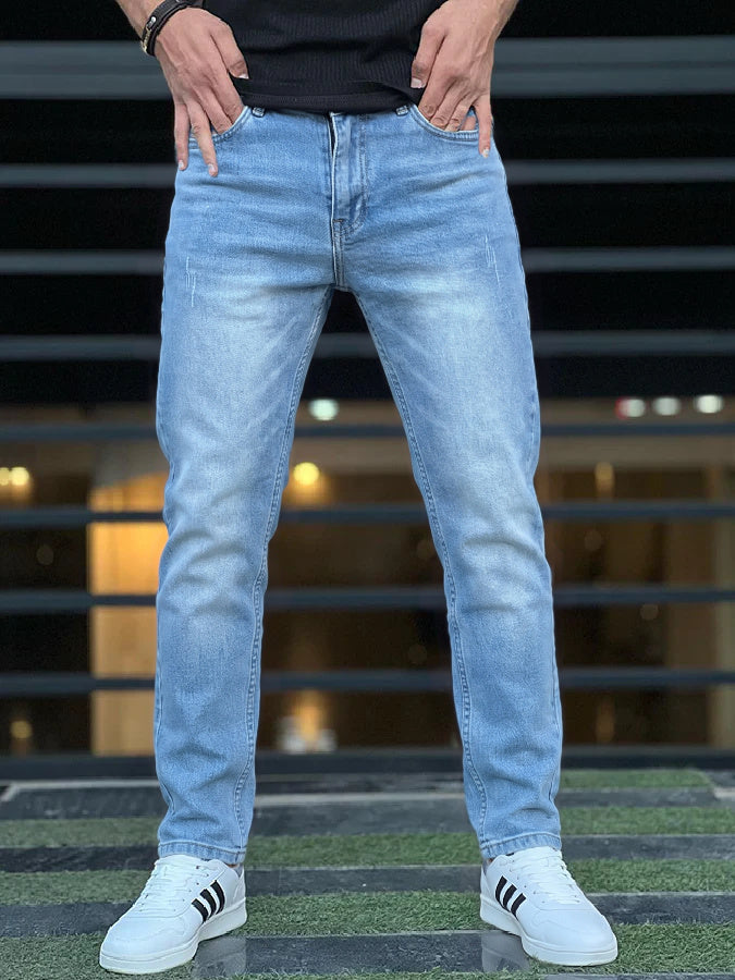 Man wearing light blue jeans with faded thighs and plain hems over white trainers | Chaps London