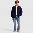 Man wearing a navy oversized rib knit zip cardigan open over a white T-shirt with jeans, full length | Chaps London