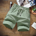 Sage green cotton drawstring shorts laid flat on wooden surface | Chaps London