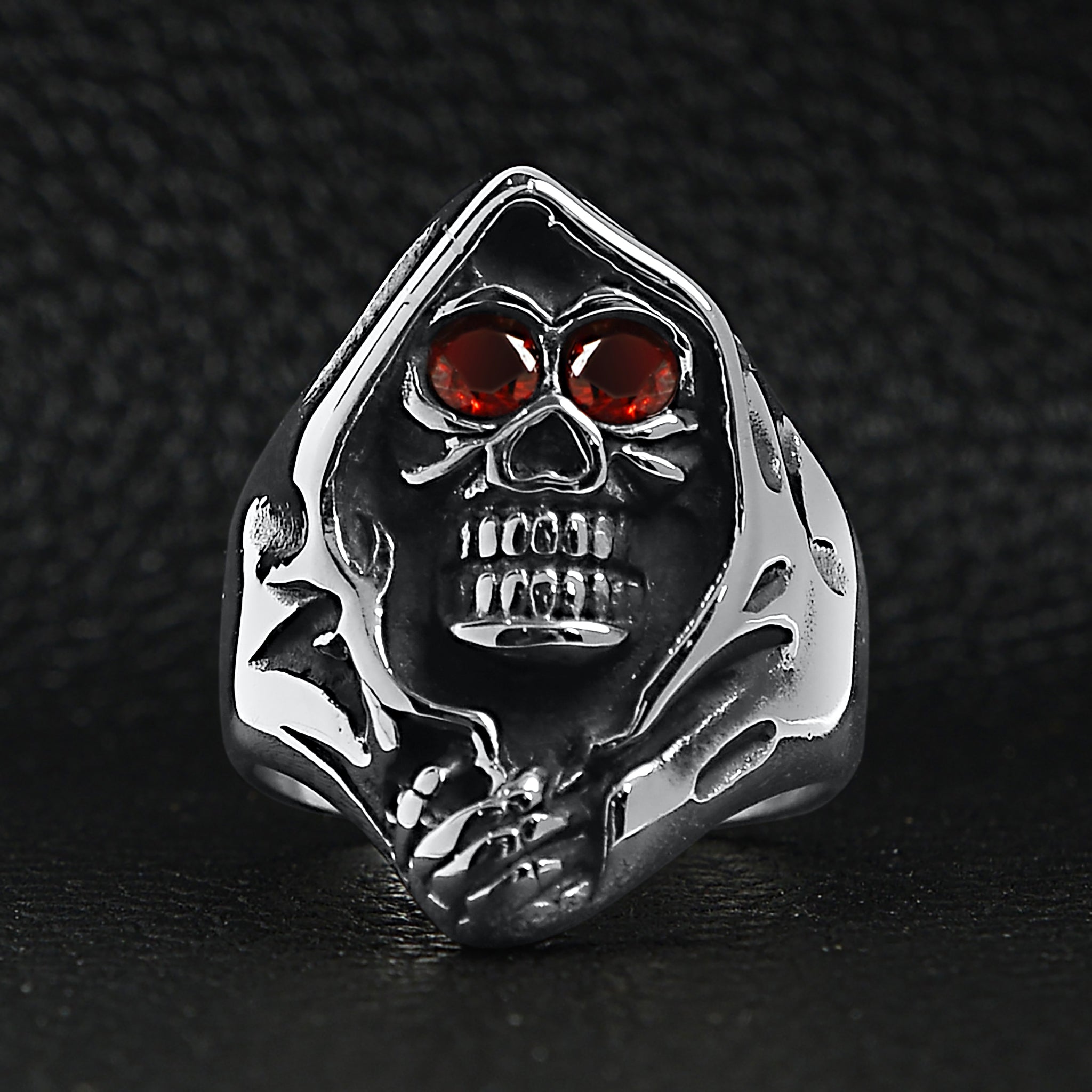 Silver hooded skull ring with red eyes, flat on dark surface | Chaps London