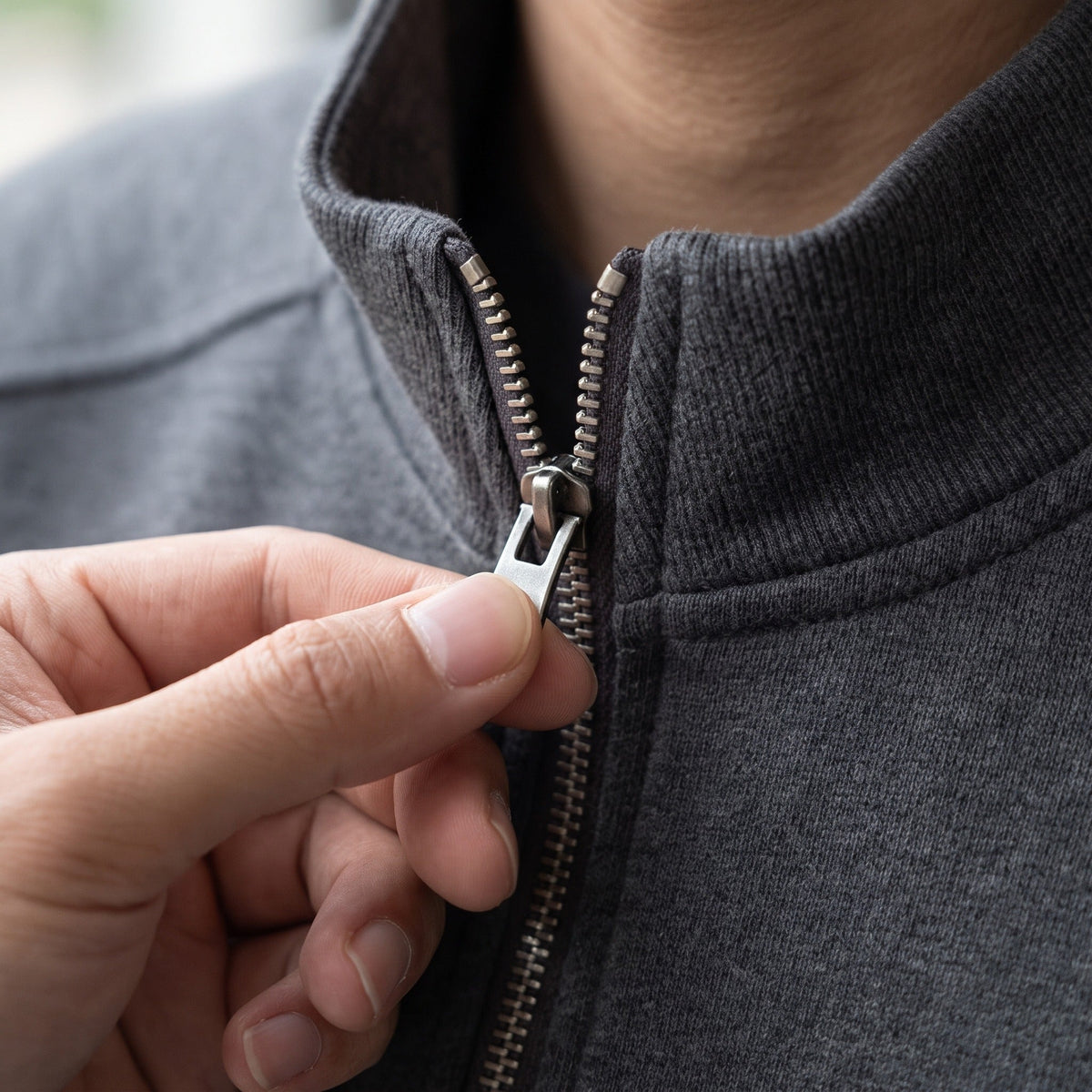 Person zipping up gray stand collar sweat jacket, close-up view | Chaps London
