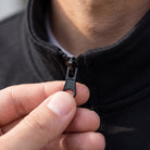 Black stand collar zip jacket close-up, worn by person, hand on zipper | Chaps London