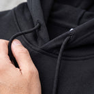 Close-up of black hoodie drawstring and hood, worn by a person | Chaps London