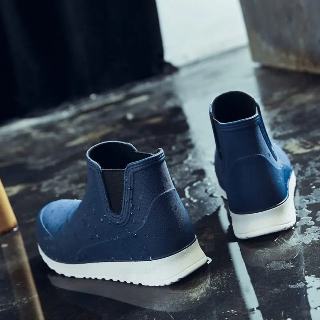 Navy blue Chelsea ankle rain boots with white soles, shown on wet ground | Chaps London