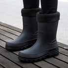 Black mid-calf rain boots with fleece cuffs, worn on person's feet | Chaps London