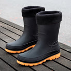 Black mid-calf rain boots with fleece cuffs and orange sole, standing on wood | Chaps London