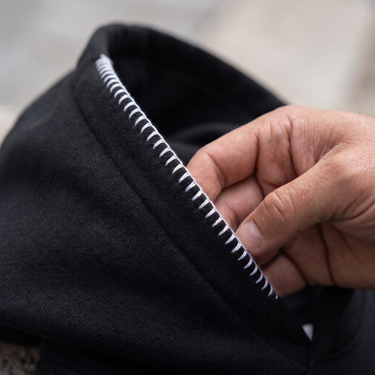 Black hoodie with white striped trim hood, worn, close-up view | Chaps London
