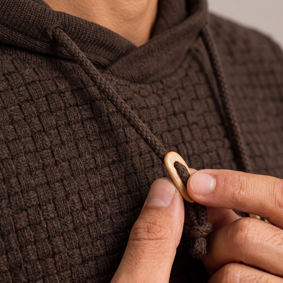 Worn dark brown basket weave hoodie with wooden toggle drawstring detail close-up | Chaps London