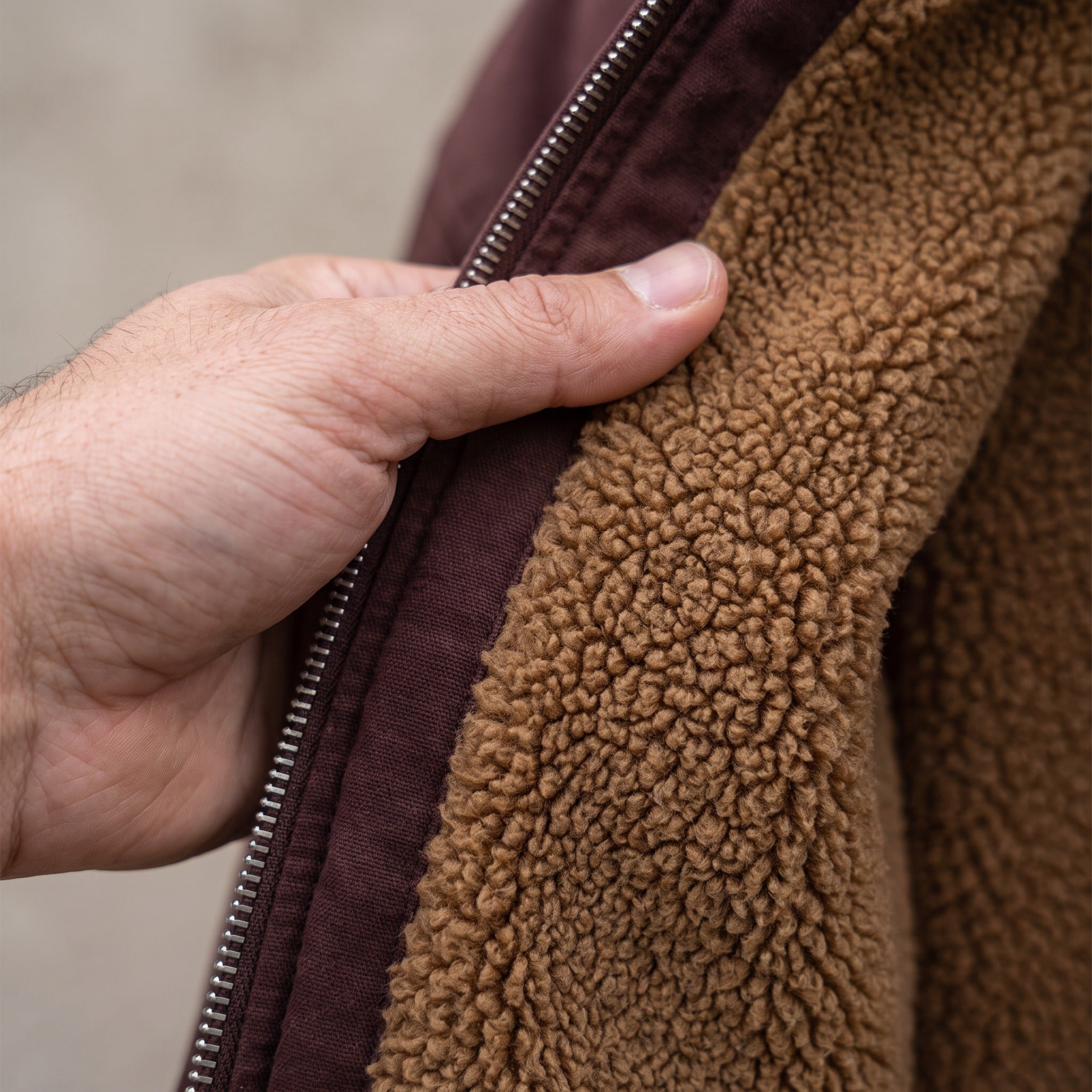 Hand opening brown jacket zipper, revealing sherpa lining, worn by person | Chaps London