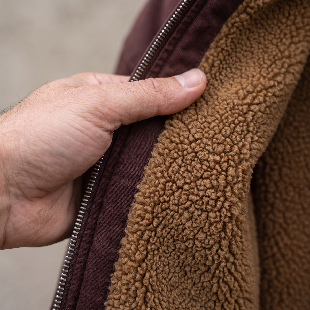 Hand opening brown jacket zipper, revealing sherpa lining, worn by person | Chaps London