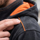 Close-up of charcoal hoodie shoulder seam with orange contrast piping, worn by person | Chaps London