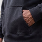 Black hoodie pocket close-up, worn by person with hand inside | Chaps London