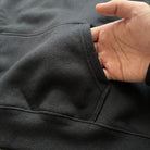 Close-up of black hoodie kangaroo pocket with hand reaching inside | Chaps London
