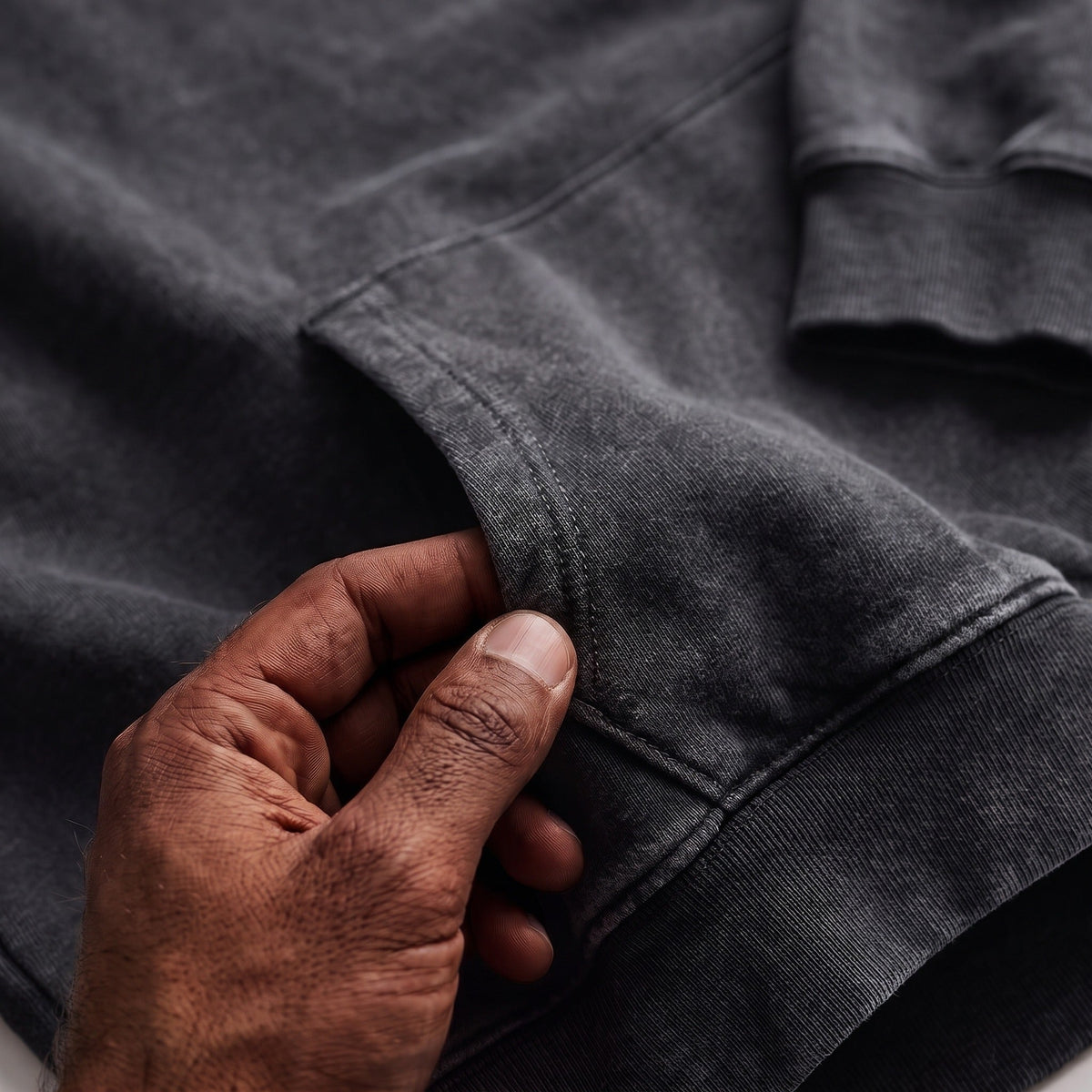Hand touching kangaroo pocket on charcoal grey washed hoodie fabric | Chaps London