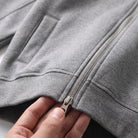 Close-up of hand unzipping grey two-way zipper on cropped hoodie | Chaps London
