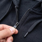 Close-up of black zipper pull and drawstring hood on worn hoodie | Chaps London
