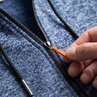 Close-up of hand pulling blue marl zip hoodie zipper with orange tab | Chaps London