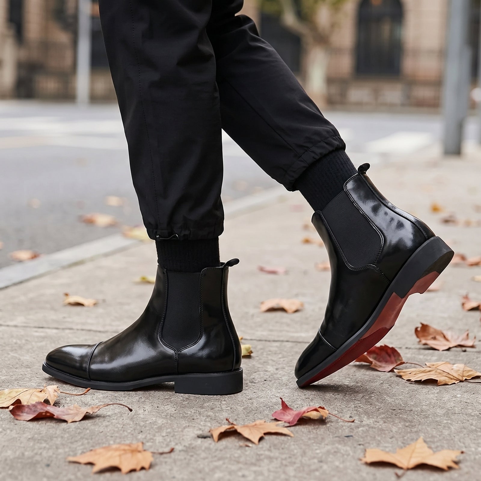 Black faux leather Chelsea boots with red sole, worn by person walking outdoors | Chaps London