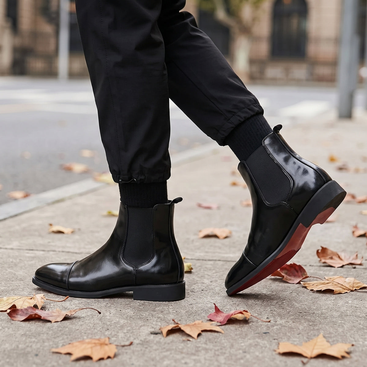 Black faux leather Chelsea boots with red sole, worn by person walking outdoors | Chaps London