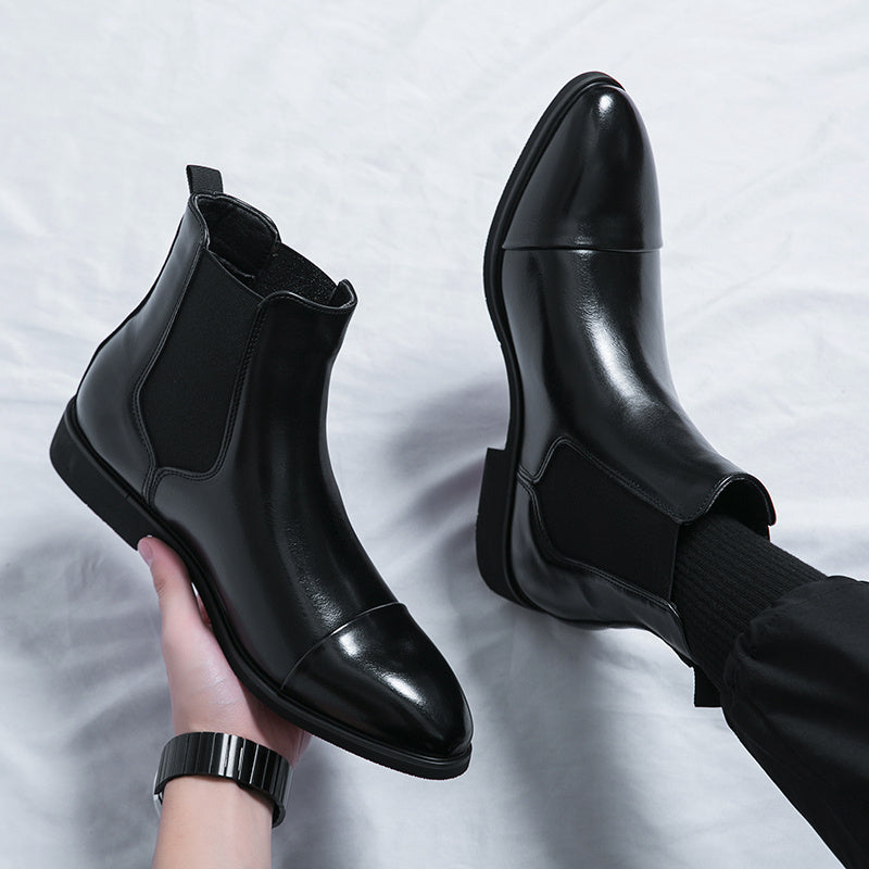 Black faux leather Chelsea boots, one worn, one held by hand | Chaps London