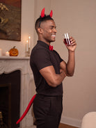 Model in the devil set raising a glass at a Halloween party