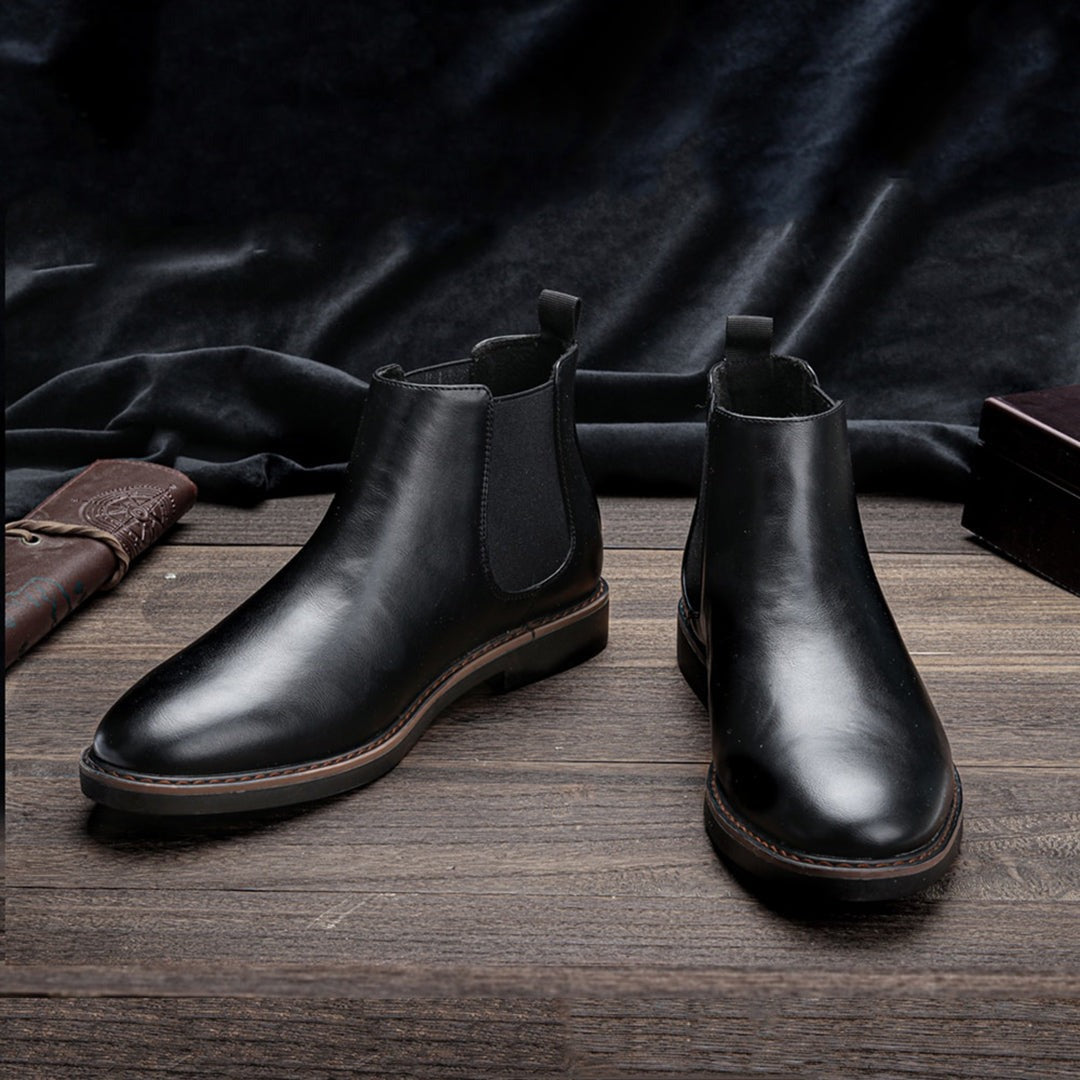 Black leather Chelsea ankle boots with elastic side panels, displayed on wooden surface | Chaps London