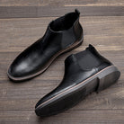 Black leather Chelsea boots with elastic side panels, shown flat on wood | Chaps London