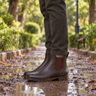 Brown Chelsea wellies on a wet park path with autumn leaves