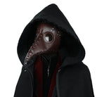 Brown plague doctor mask with rivets worn by hooded person | Chaps London
