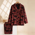 Red and black pyjama set with pumpkin print, hanging on wooden hanger | Chaps London