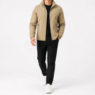 Man wearing beige zip-up jacket with black pants and white sneakers | Chaps London