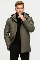 Man wearing olive green hooded parka jacket with black turtleneck and trousers | Chaps London