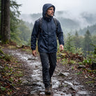 Man wearing navy waterproof hooded rain jacket, hiking on misty forest trail | Chaps London