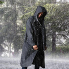 Man wearing black hooded waterproof raincoat standing outdoors in heavy rain | Chaps London
