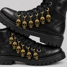 Gold skull charms with lobster clasps hanging from black boot laces | Chaps London
