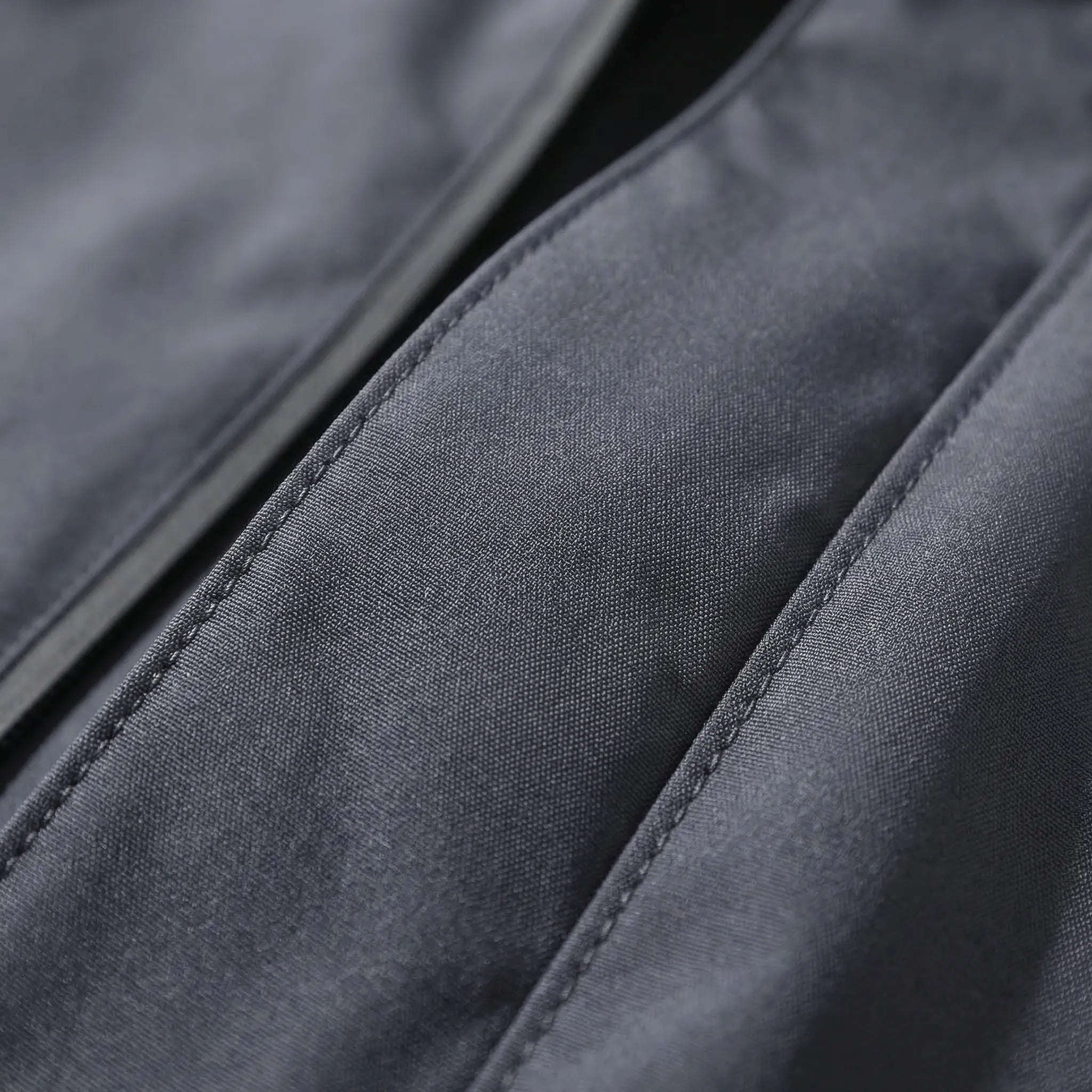 Close-up of dark gray jacket fabric showing zipper and stitched seams | Chaps London